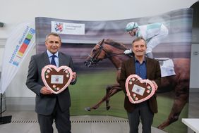 Oberbürgermeister Thomas Geisel (r.) und Klaus Allofs, Vorstand des Düsseldorfer Reiter- und Rennvereins, mit Lebkuchenherzen, die beim 100. "Großen Preis der Landeshauptstadt" auf der Rennbahn verteilt werden.