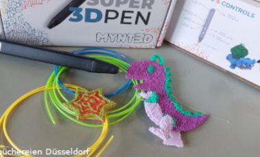 Foto mit 3D-Druck-Stift, einem gebastelten Dino, Filament in verschiedenen Farben und einem Buch mit Anleitungen