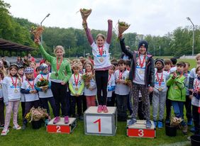 Foto fon einer Siegerehrung, Kinder stehen mit Medaille und Blumen auf Siegertreppchen mit ersen, zweitenm und dritten Platz