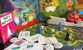 Foto mit mehreren Brettspielen und Spielelementen wie Spielefigurgen und Würfel.