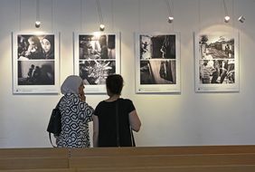 Das Foto zeigt zwei Frauen von hinten, während sie vier Bilder der Ausstellung 'Auf der Flucht. Frauen und Migration' in der Johanneskirche betrachten © Landeshauptstadt Düsseldorf