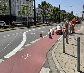 Foto von Straßenarbeitern beim Markieren des neuenen Radfahrstreifens auf der Luegallee.