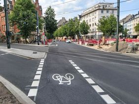 Foto von der neu asphaltierten und markierten Merowingerstraße mit Einmündung zur Brunnenstraße
