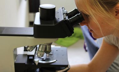 Eine Frau blickt durch ein Mikroskop