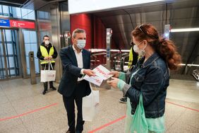 OB Thomas Geisel übergibt einer Passantin ein Hygienekit im U-Bahnhof Heinrich-Heine-Allee